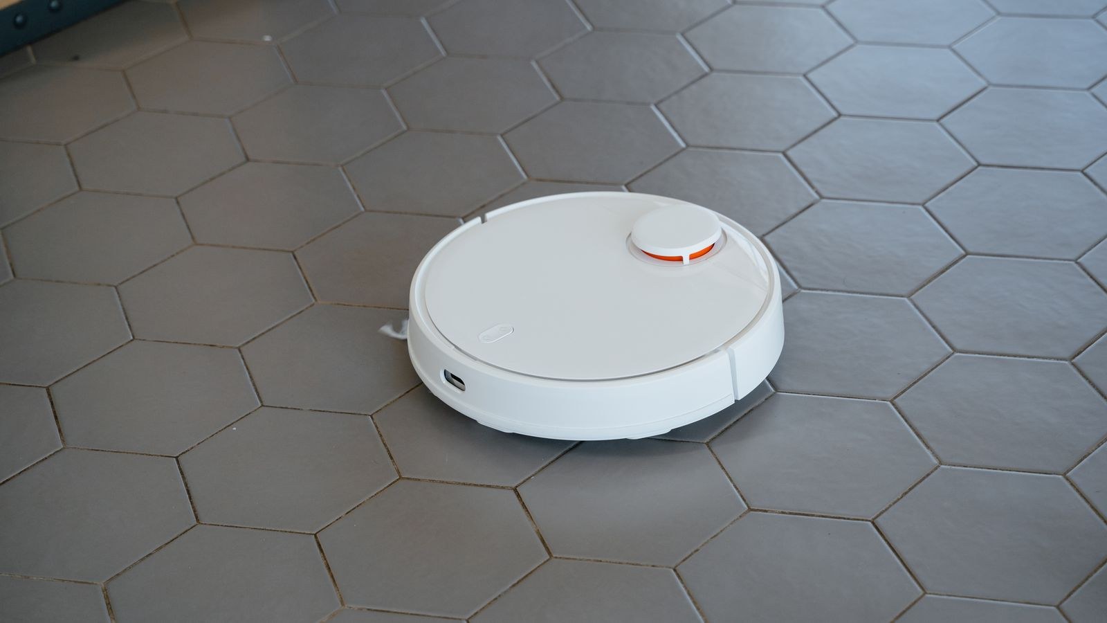 White robot vacuum cleaning a tiled floor in a bright modern home