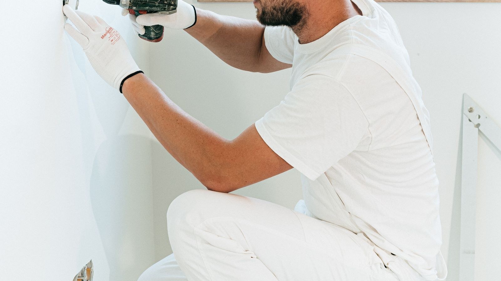Worker installing a wall box for a network outlet inside a room