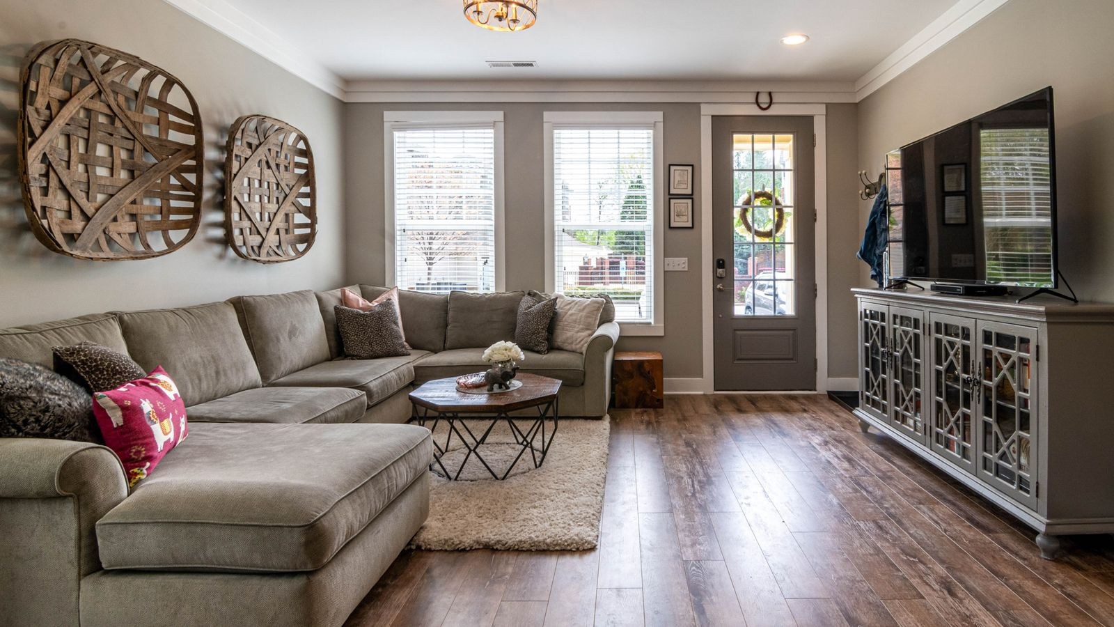 Spacious living room with a large sofa, wooden floor and neutral decor