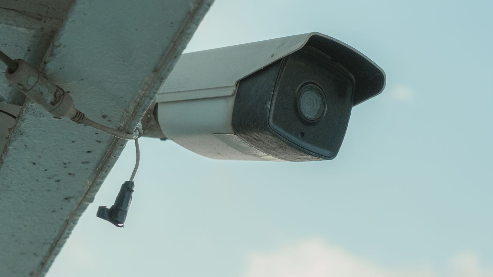 Security camera mounted on a building eave positioned for clear night vision coverage