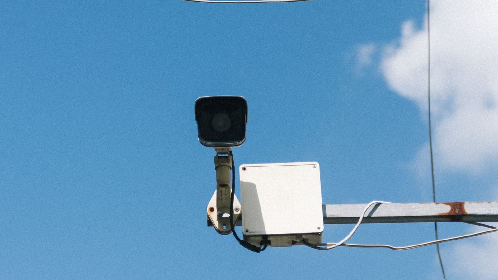 Outdoor surveillance camera mounted under a clear sky with cloud storage plan considerations