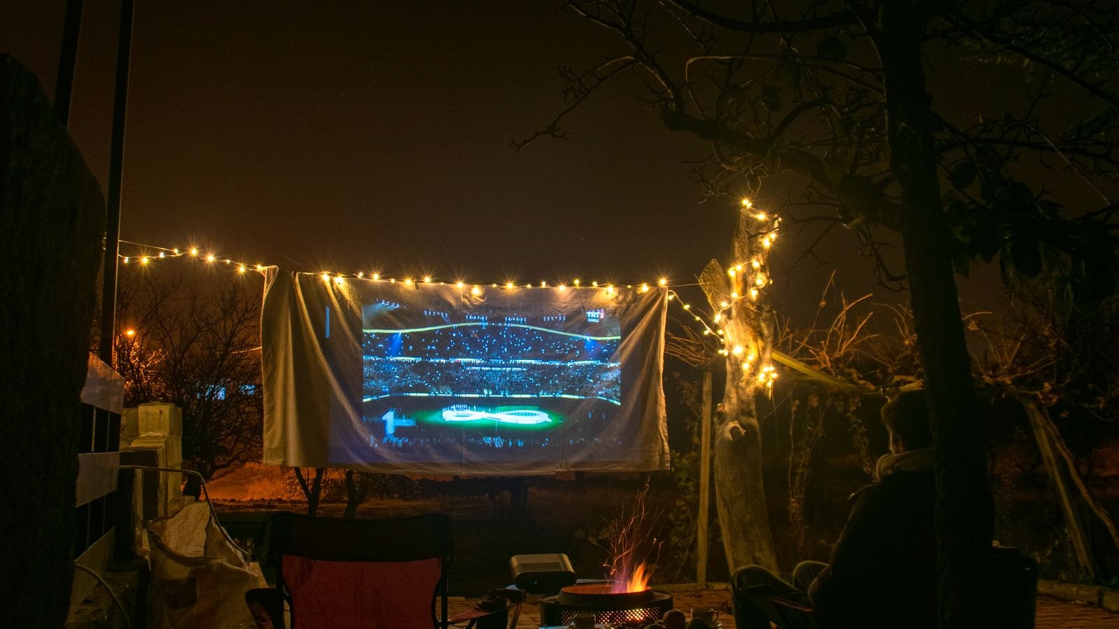 Backyard projection screen and fire pit set up for a relaxed movie evening