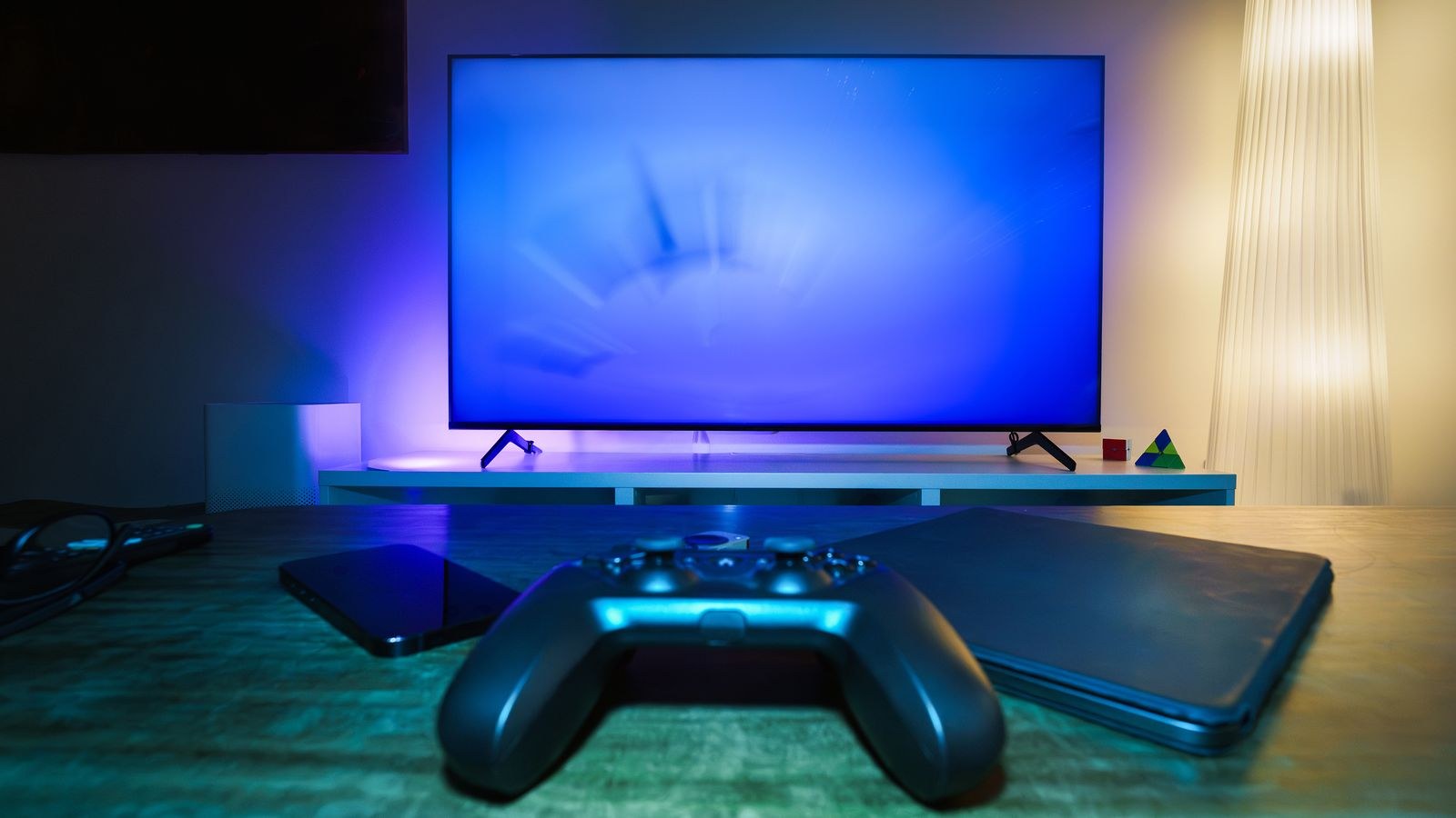Ambient gaming setup with a controller and a large TV showing gameplay