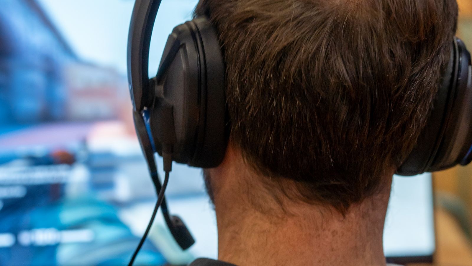 Streamer wearing headphones playing a console game at a desk