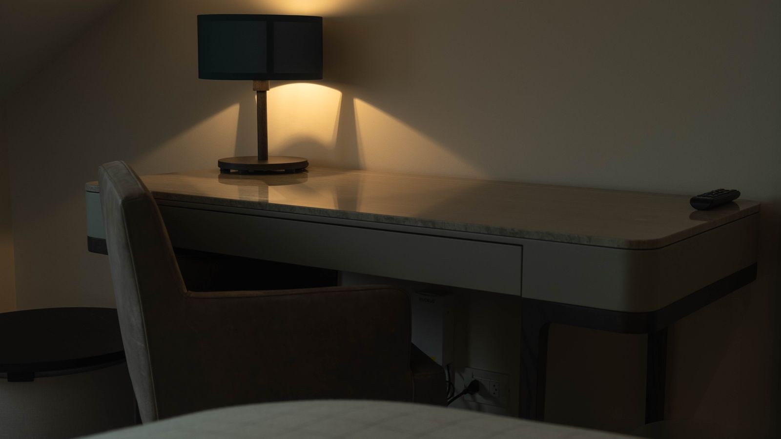 Compact bedroom desk setup with a warm lamp providing task lighting