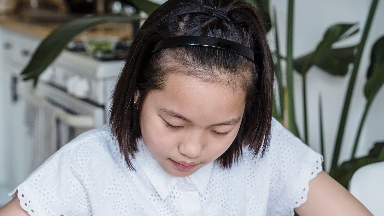 Child studying at a well lit desk with a task lamp