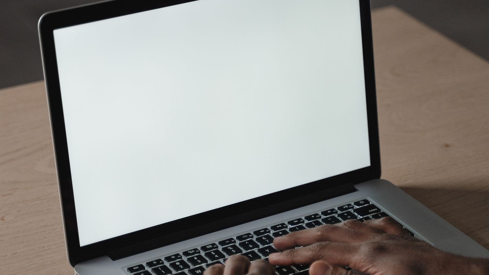 Hands typing on a laptop keyboard showing the wrist angle to avoid at a desk
