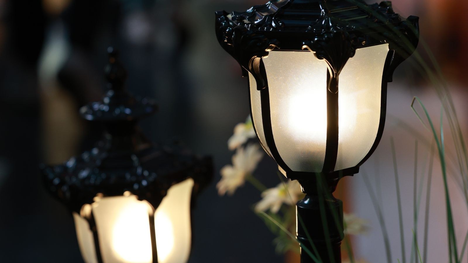 Illuminated garden path lamps along a walkway at dusk