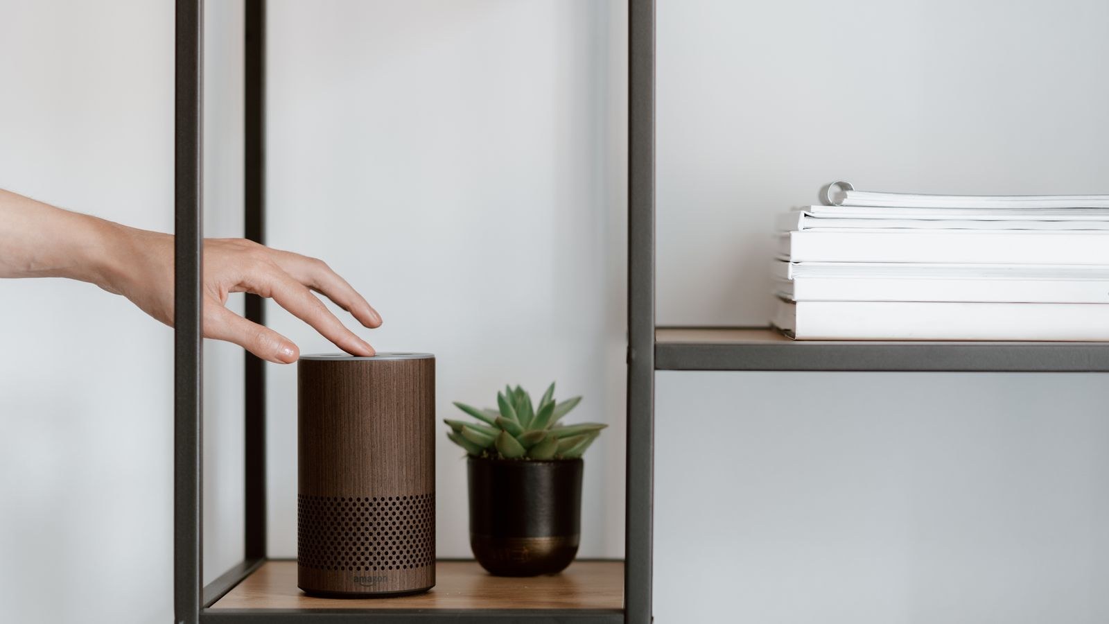Hand adjusting a smart speaker on a shelf in a simple home setup