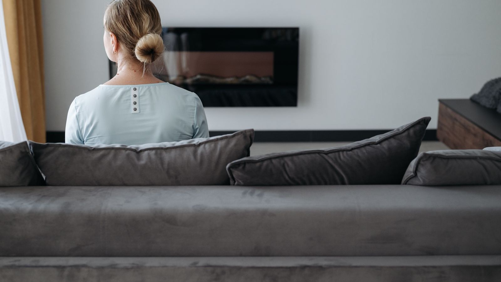 Person seated on a couch showing the rounded lower back posture that aggravates sciatica