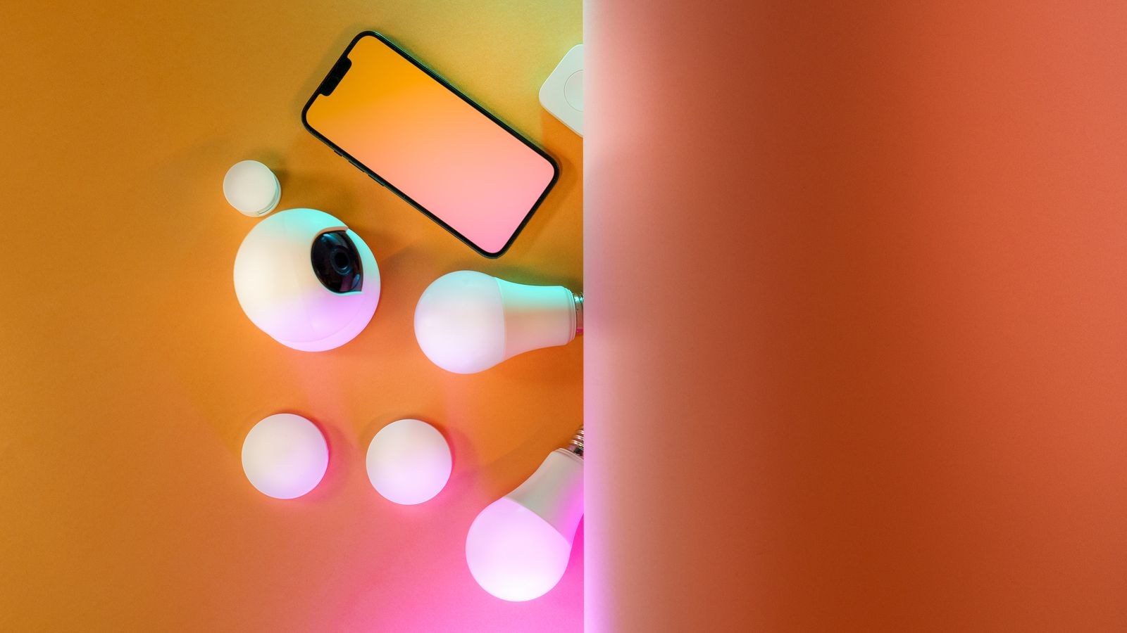 Overhead view of smart home gadgets including smartphone camera and light bulbs