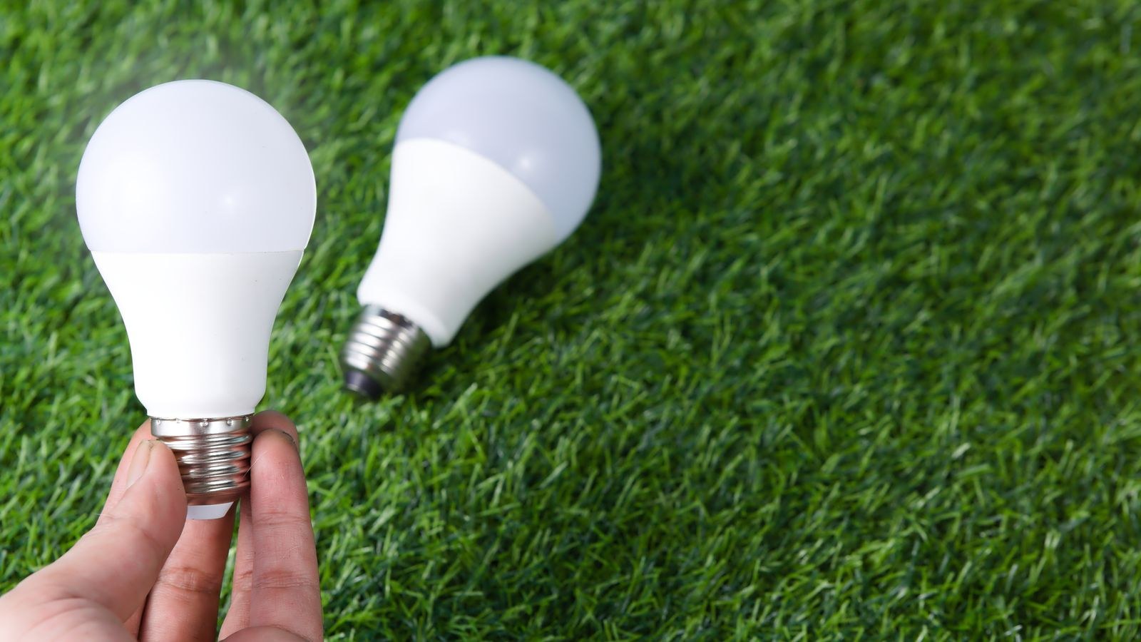 Hand holding an efficient LED bulb symbolising home energy reduction