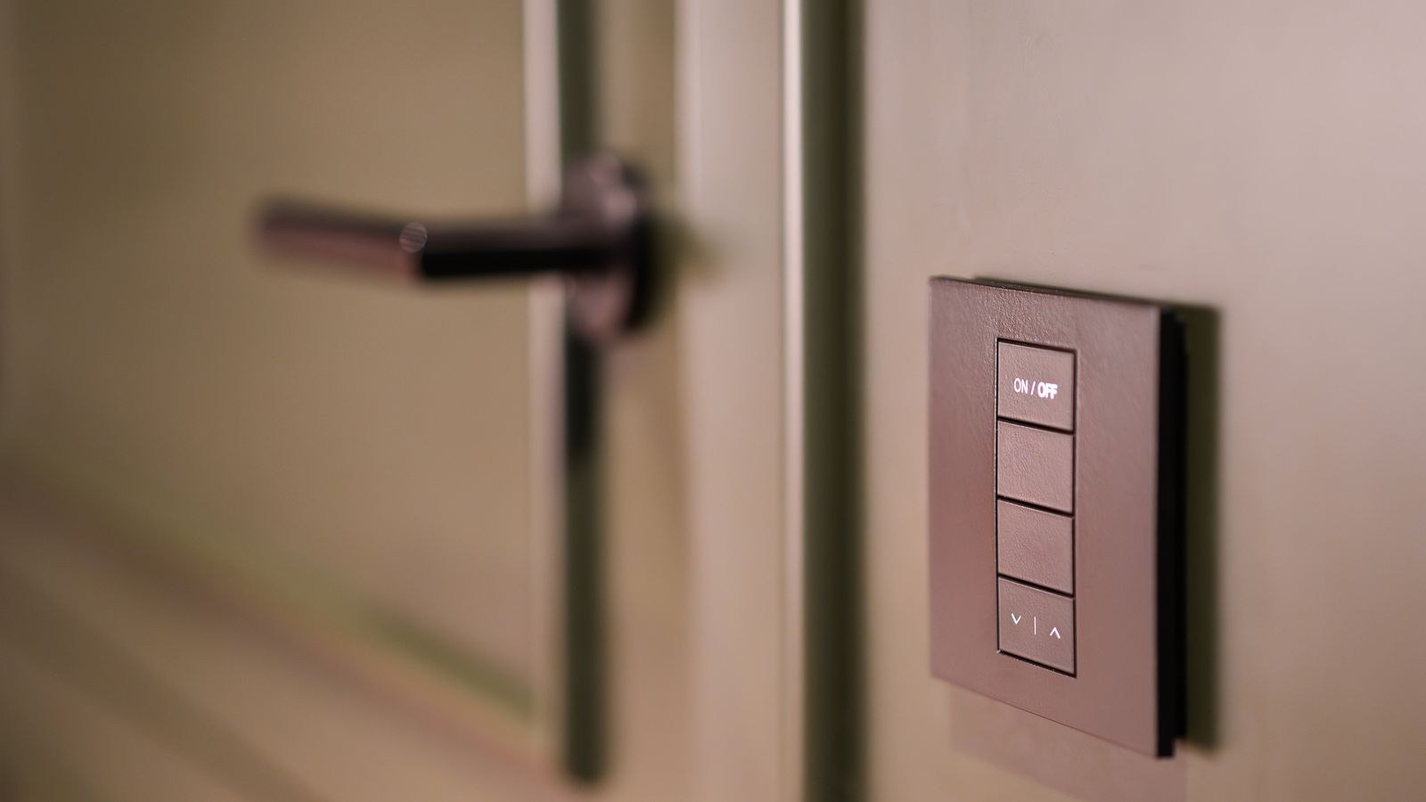 Smart home control switch beside a modern door handle in a rental unit