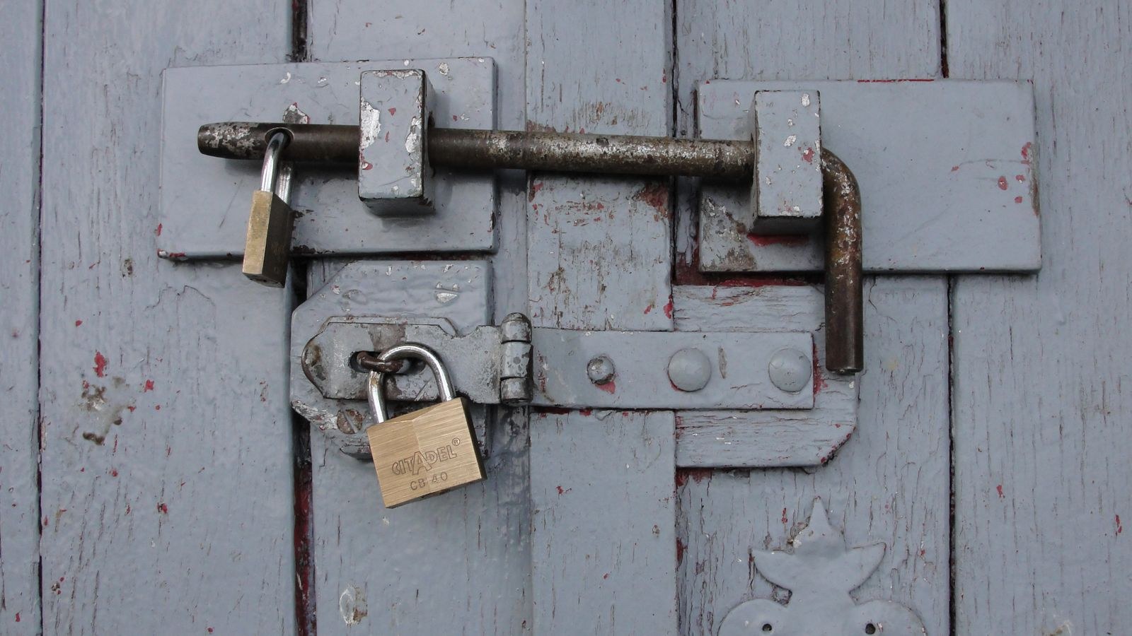 Weathered brass padlocks securing a wooden outdoor door