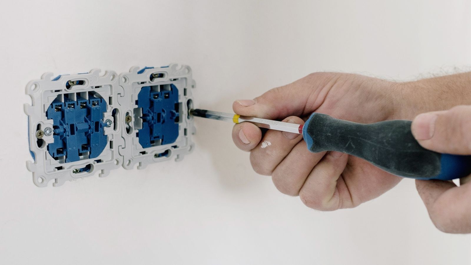 Person using a screwdriver to install a wall outlet in a home