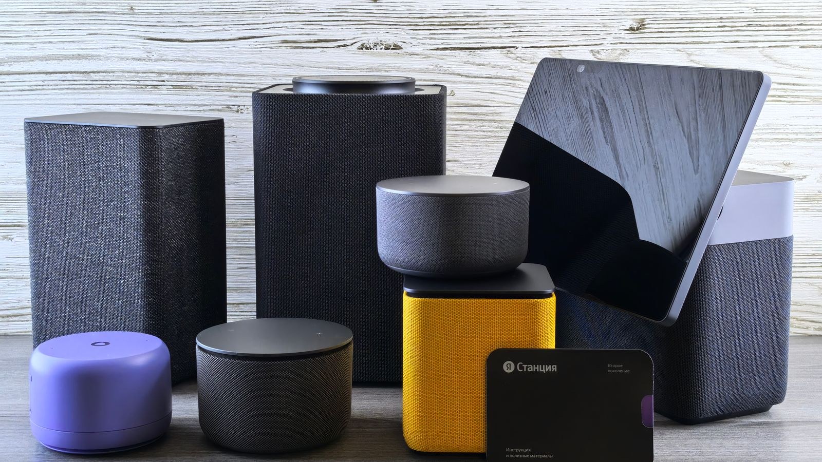 Several smart home speakers and a smart display on a wooden surface