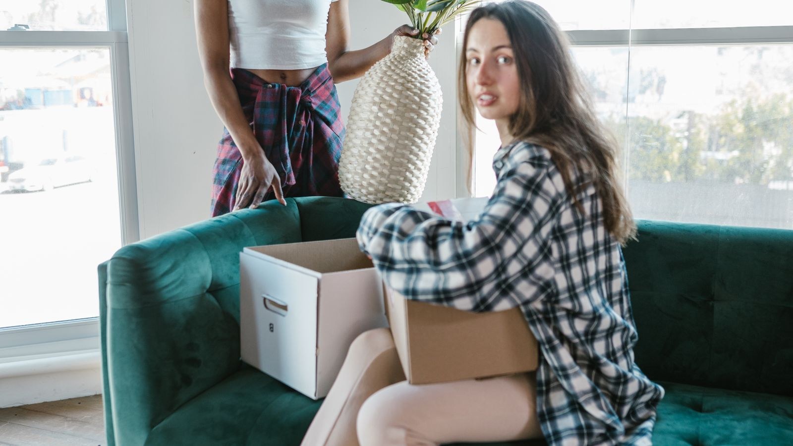 Two people relaxing on a new sofa surrounded by moving boxes