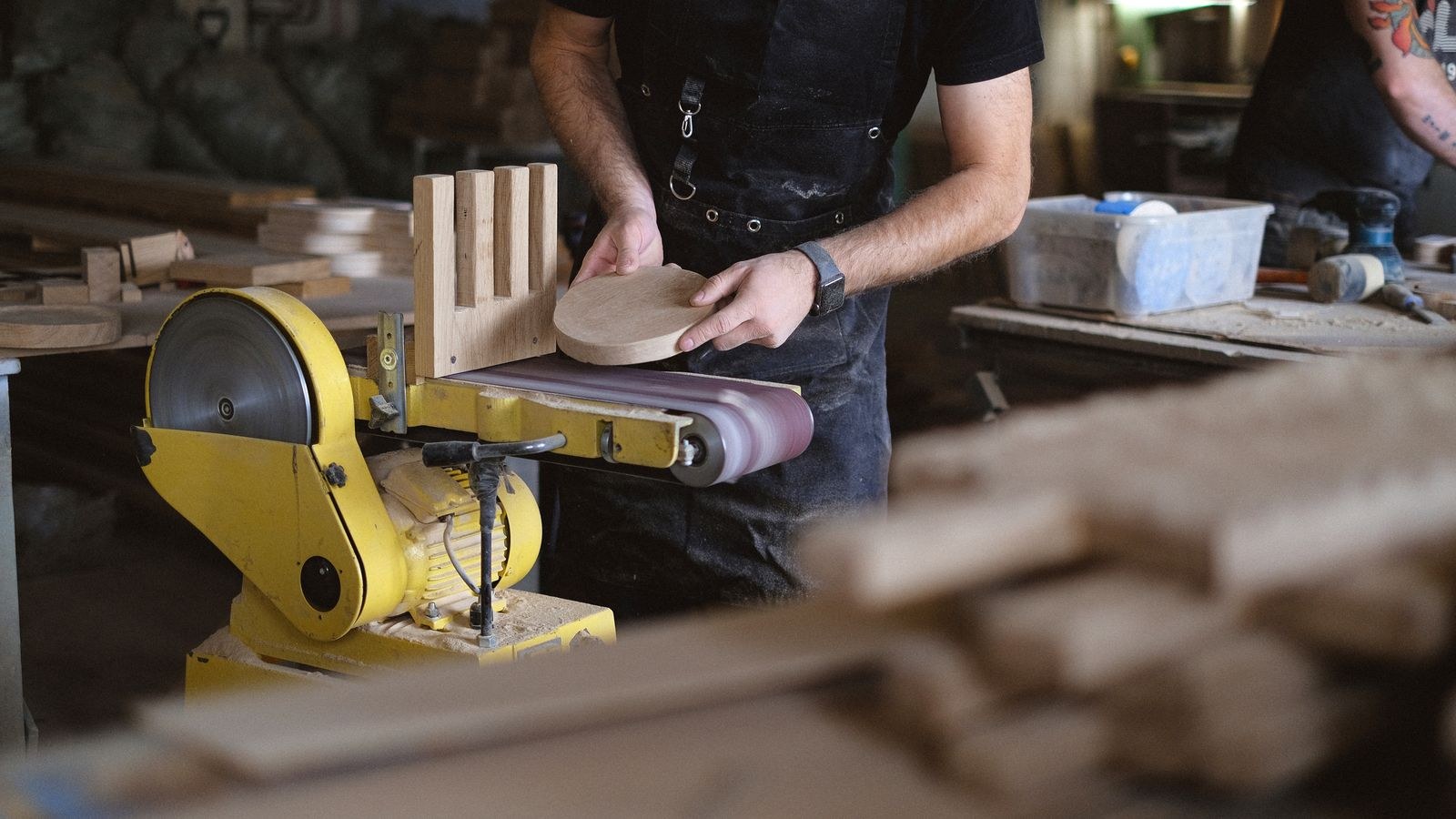 Craftsman sanding a wooden furniture component in a workshop