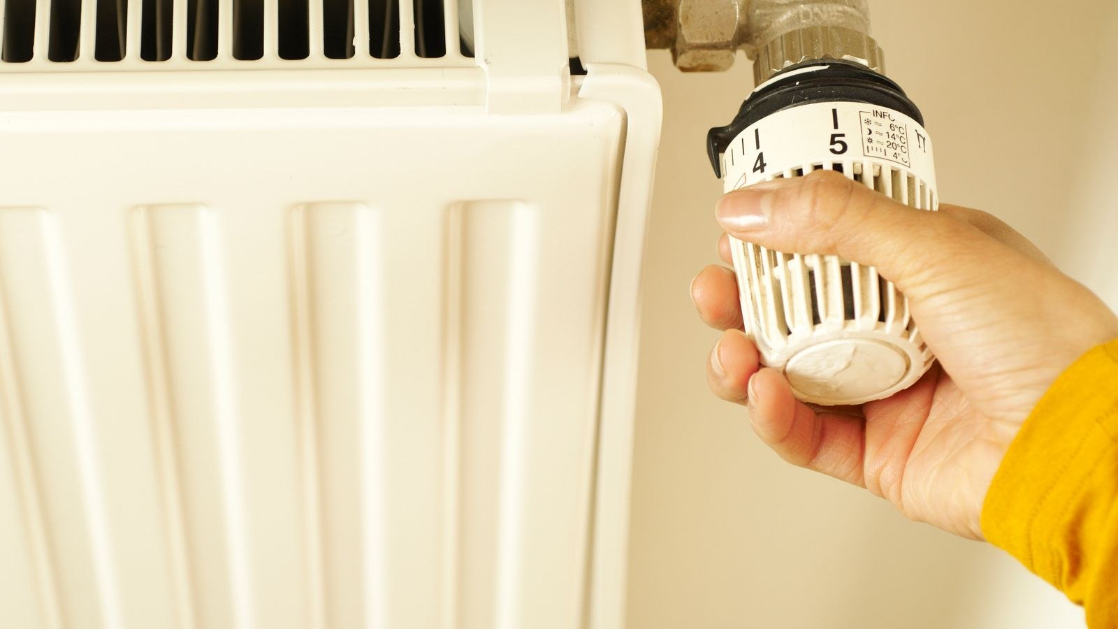 Hand adjusting a heating control valve to set room temperature