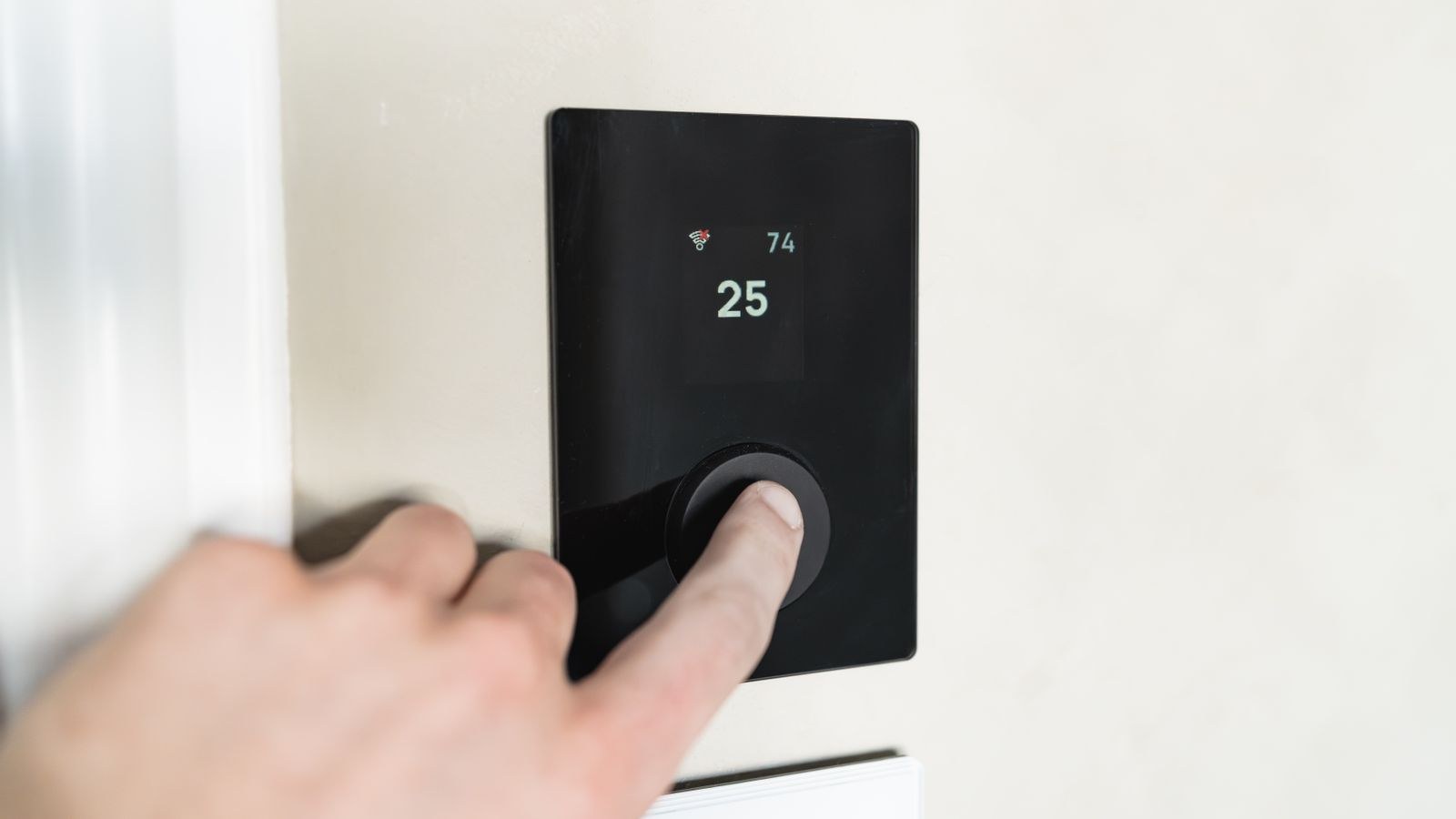 Hand adjusting a smart thermostat interface to lower home heating temperature