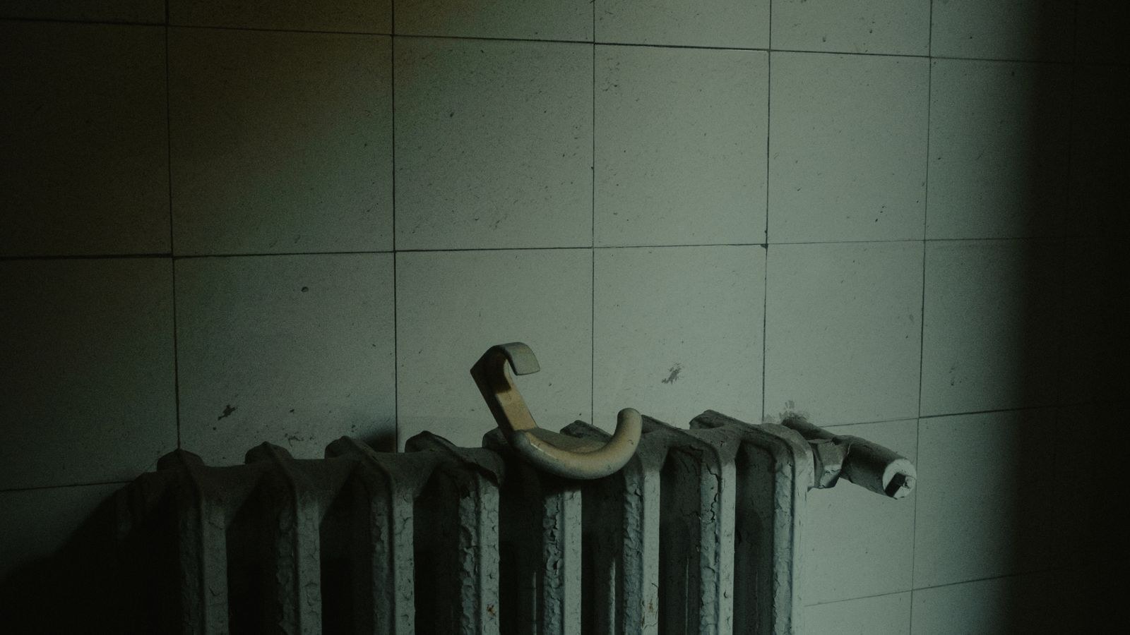 Vintage radiator against a tiled wall illustrating home heating cost