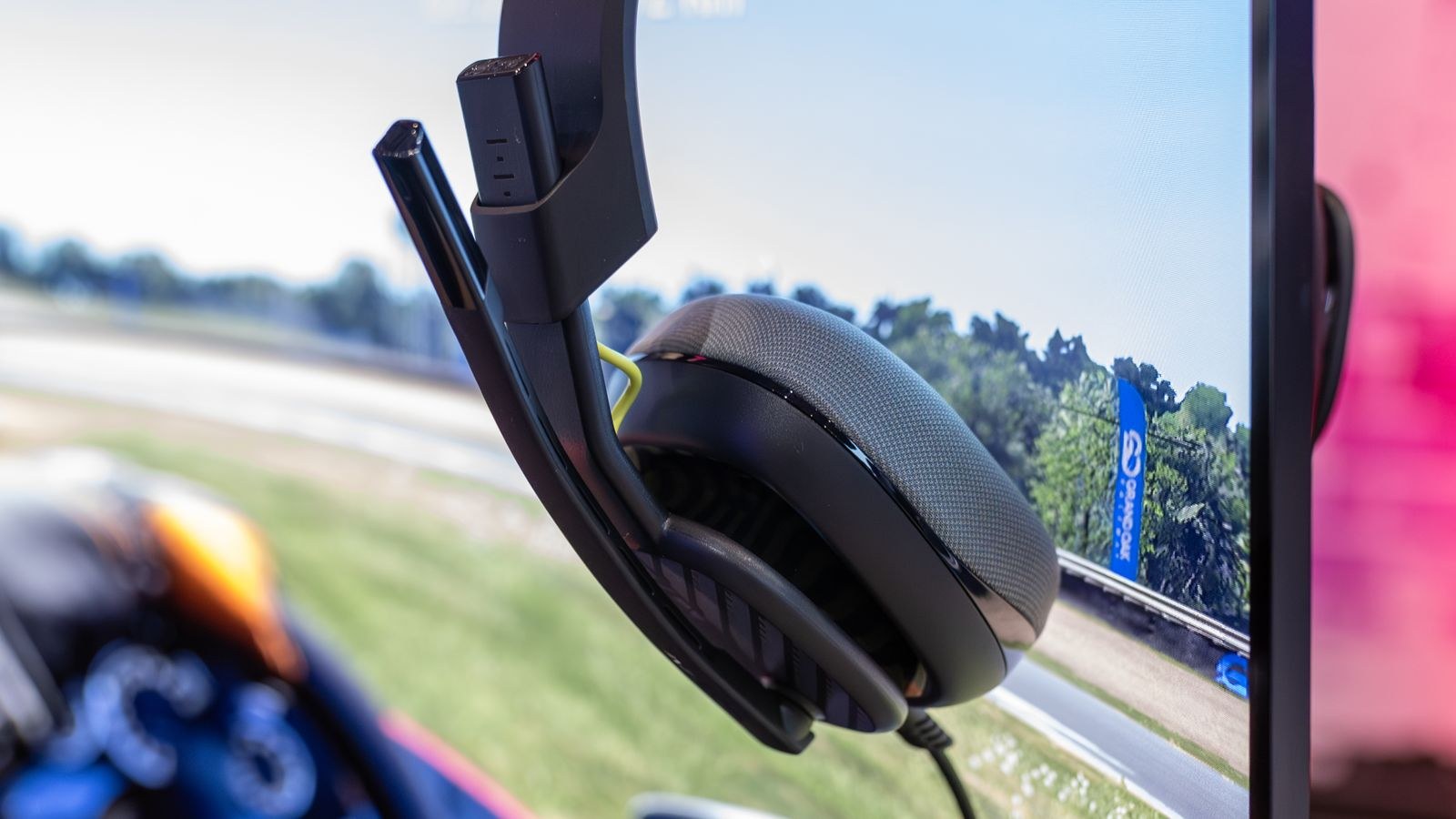 Gaming headset placed on a curved monitor in a dark gaming setup