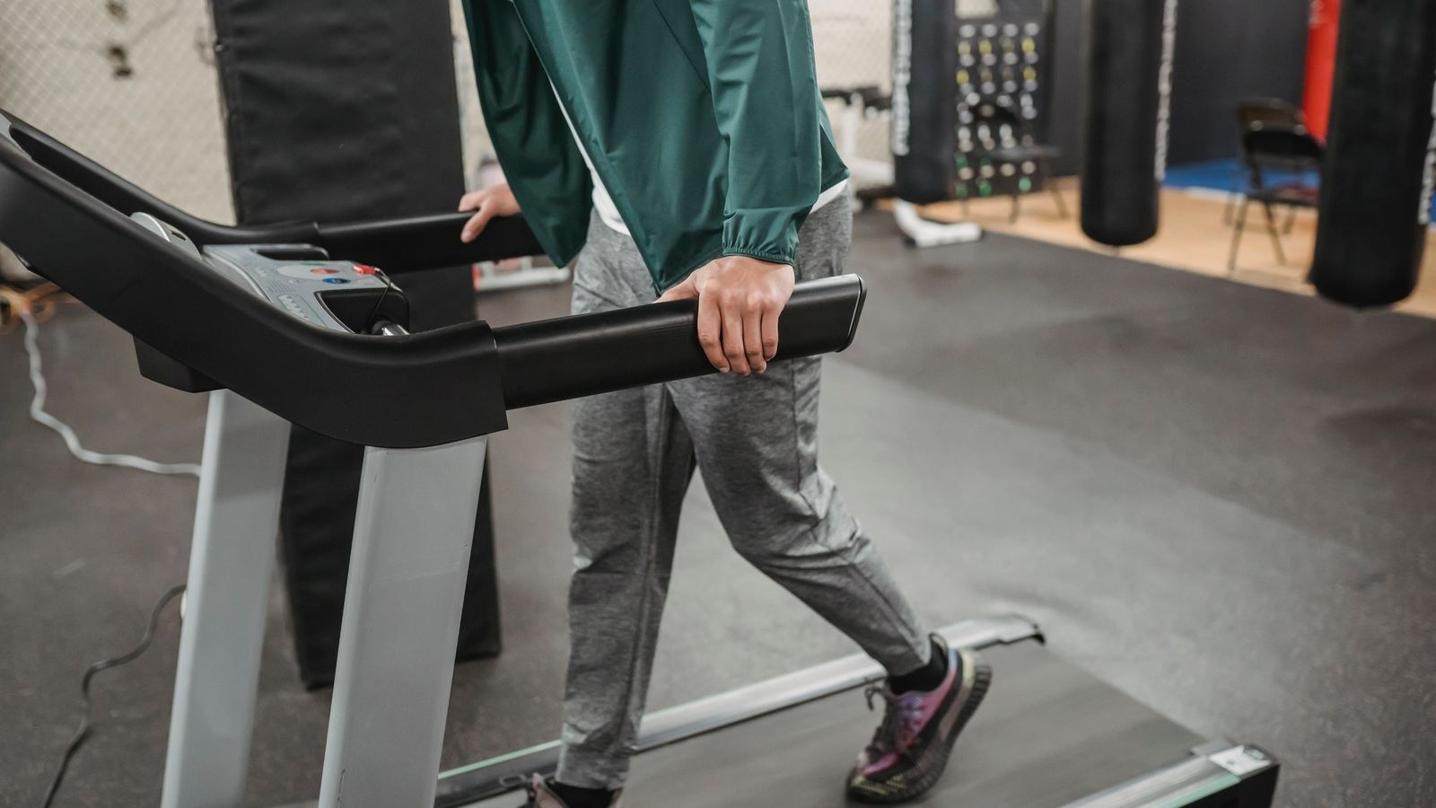 Person walking on a treadmill at a slow pace in a bright fitness space