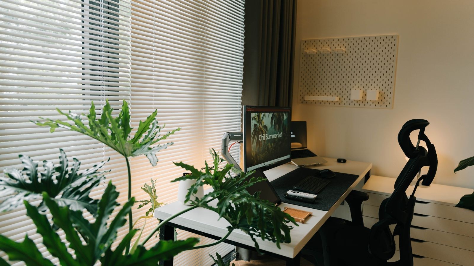Home office desk and chair beside a window with plants on a wooden floor