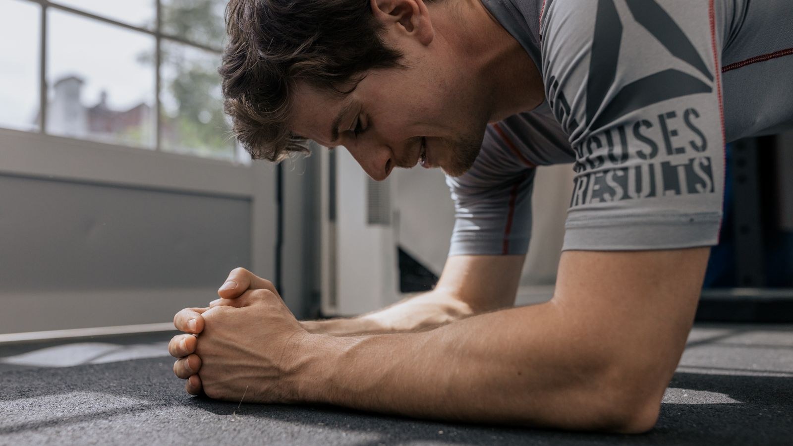 Man holding a forearm plank on a gym floor to strengthen deep core muscles