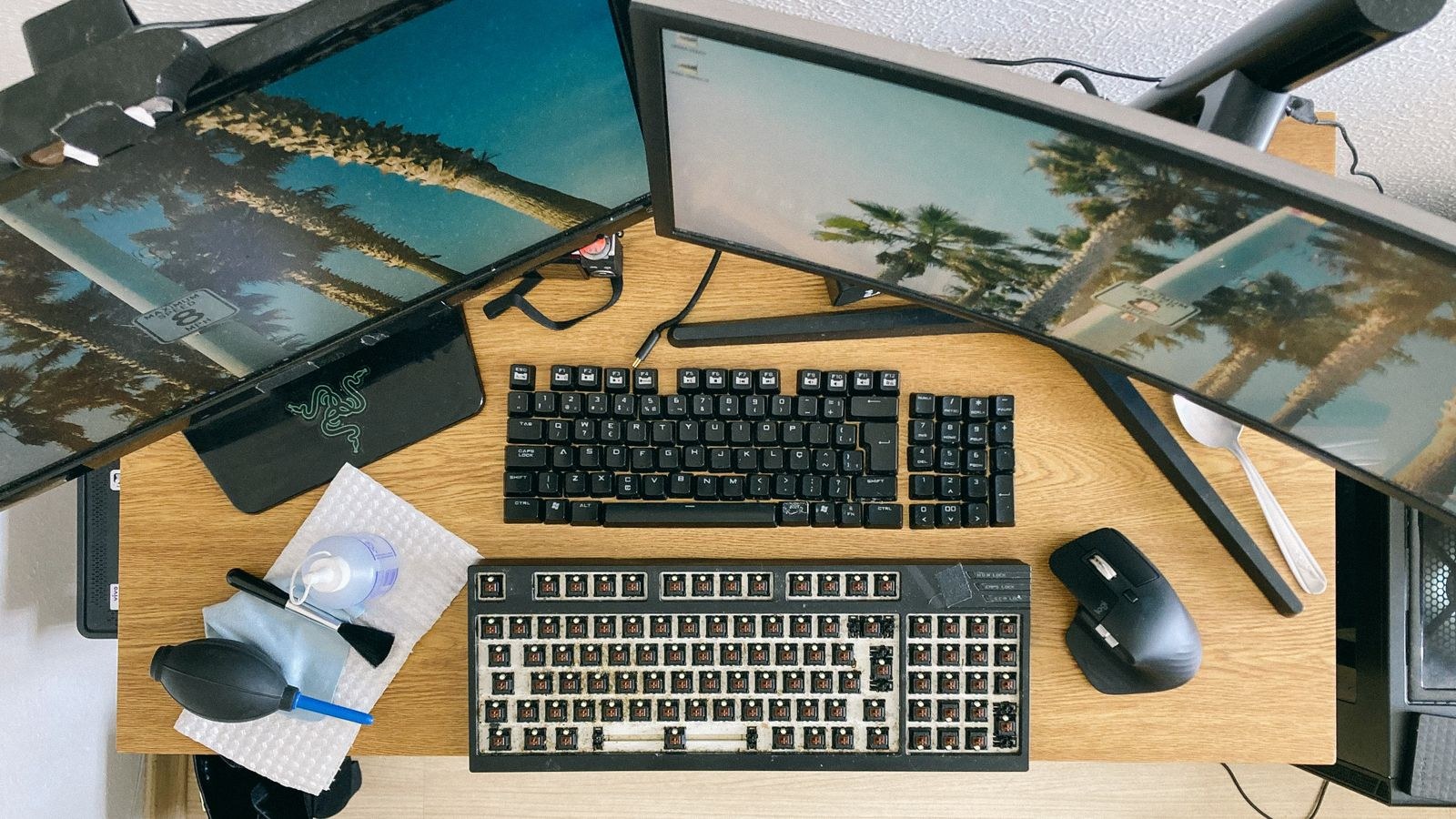 Desk with monitors and a mechanical keyboard with keycaps removed for cleaning