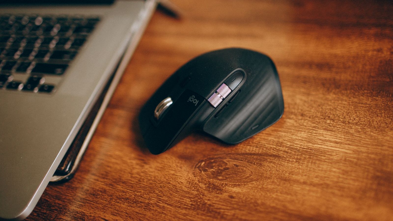 Person using a vertical mouse with a neutral handshake grip at a home office desk