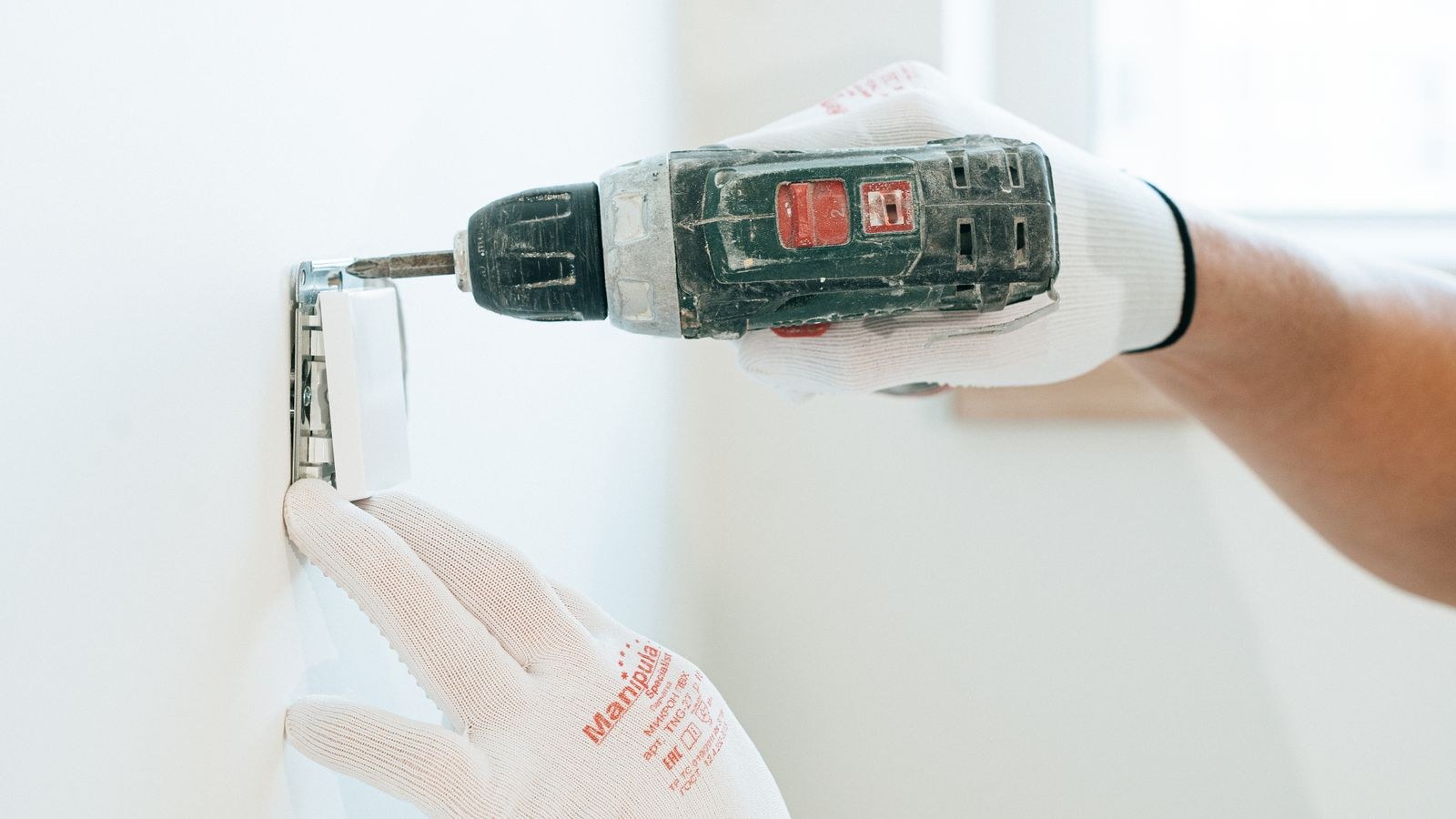 Hands installing a network wall plate and keystone jack outlet