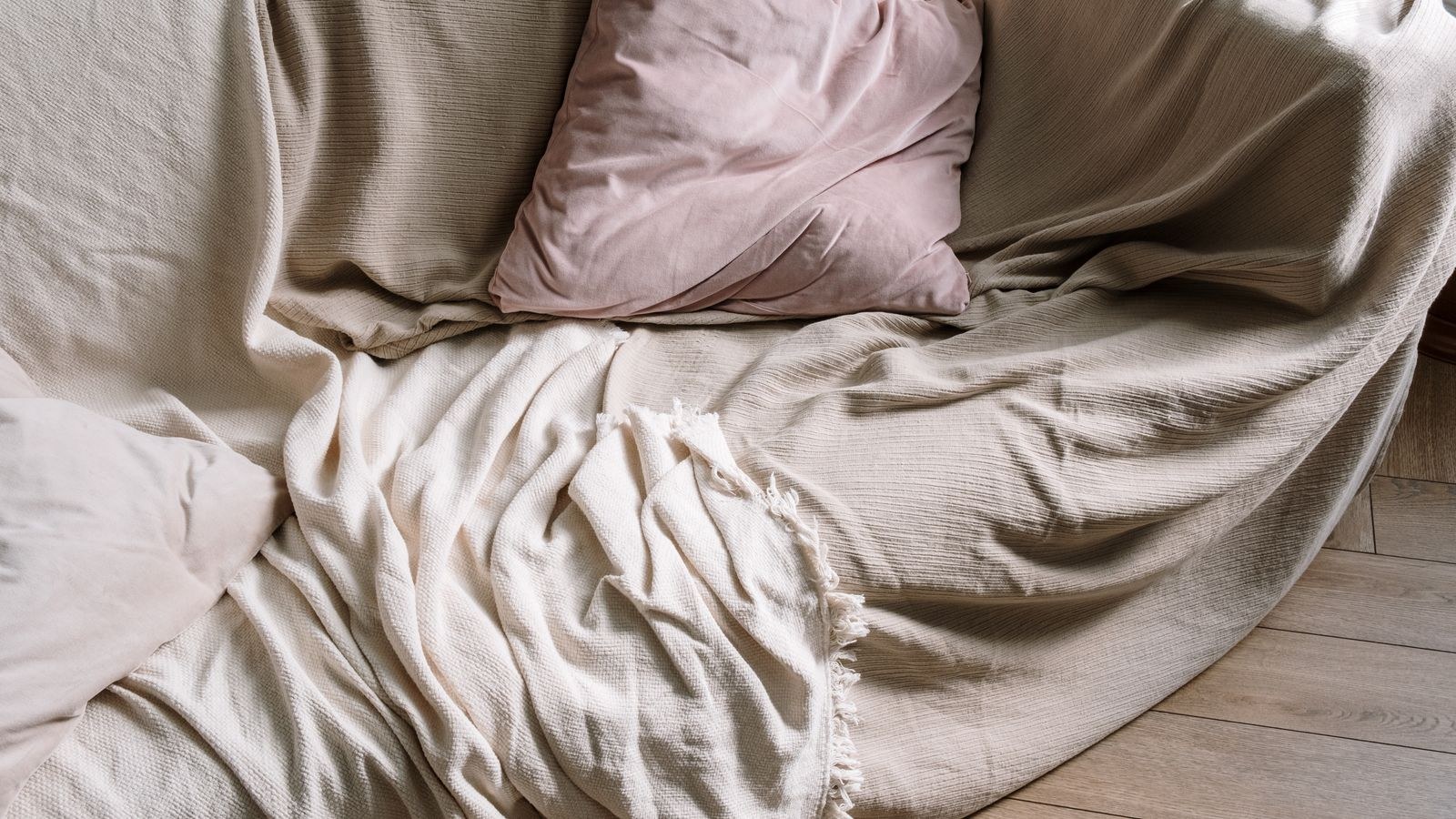 Warm knit throw blanket draped over a beige sofa with cushions