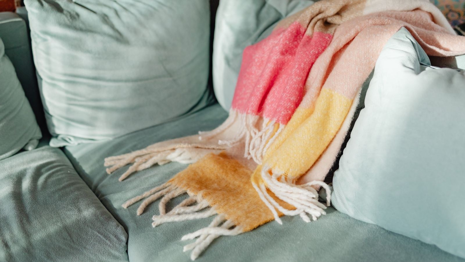 Colorful throw blanket draped across a teal sofa in a living room