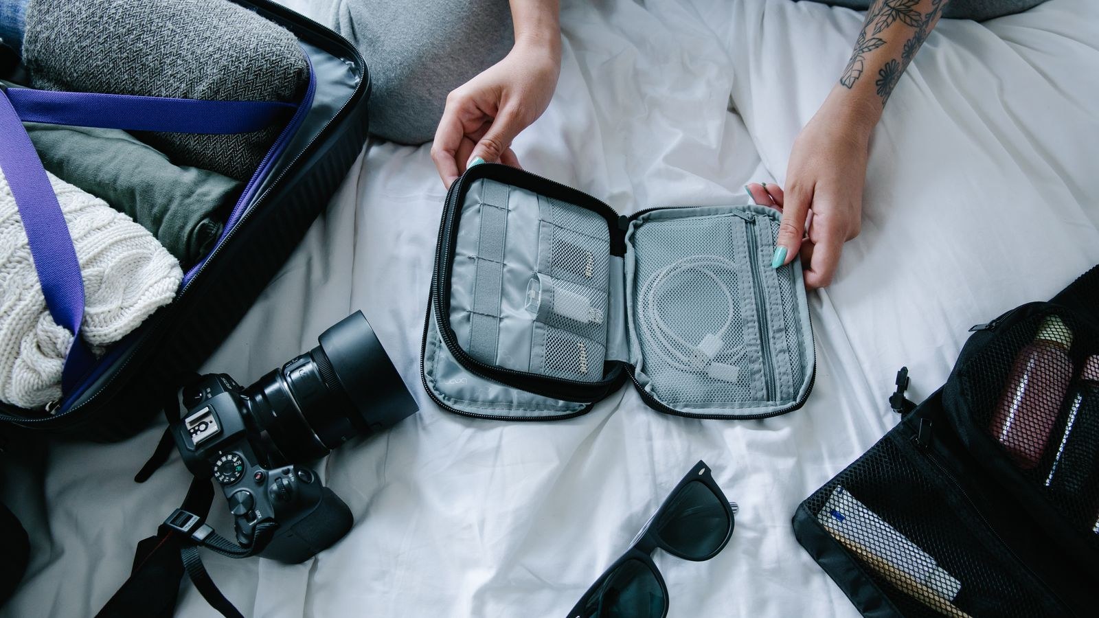 Traveler organizing tech essentials and packing cubes on a hotel bed