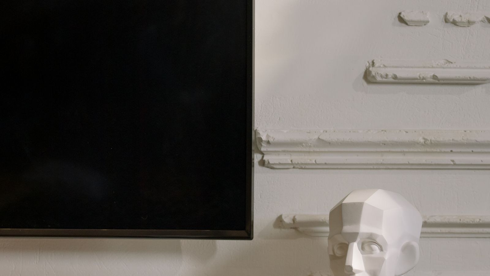 Black flat screen television mounted flush on a plain interior wall