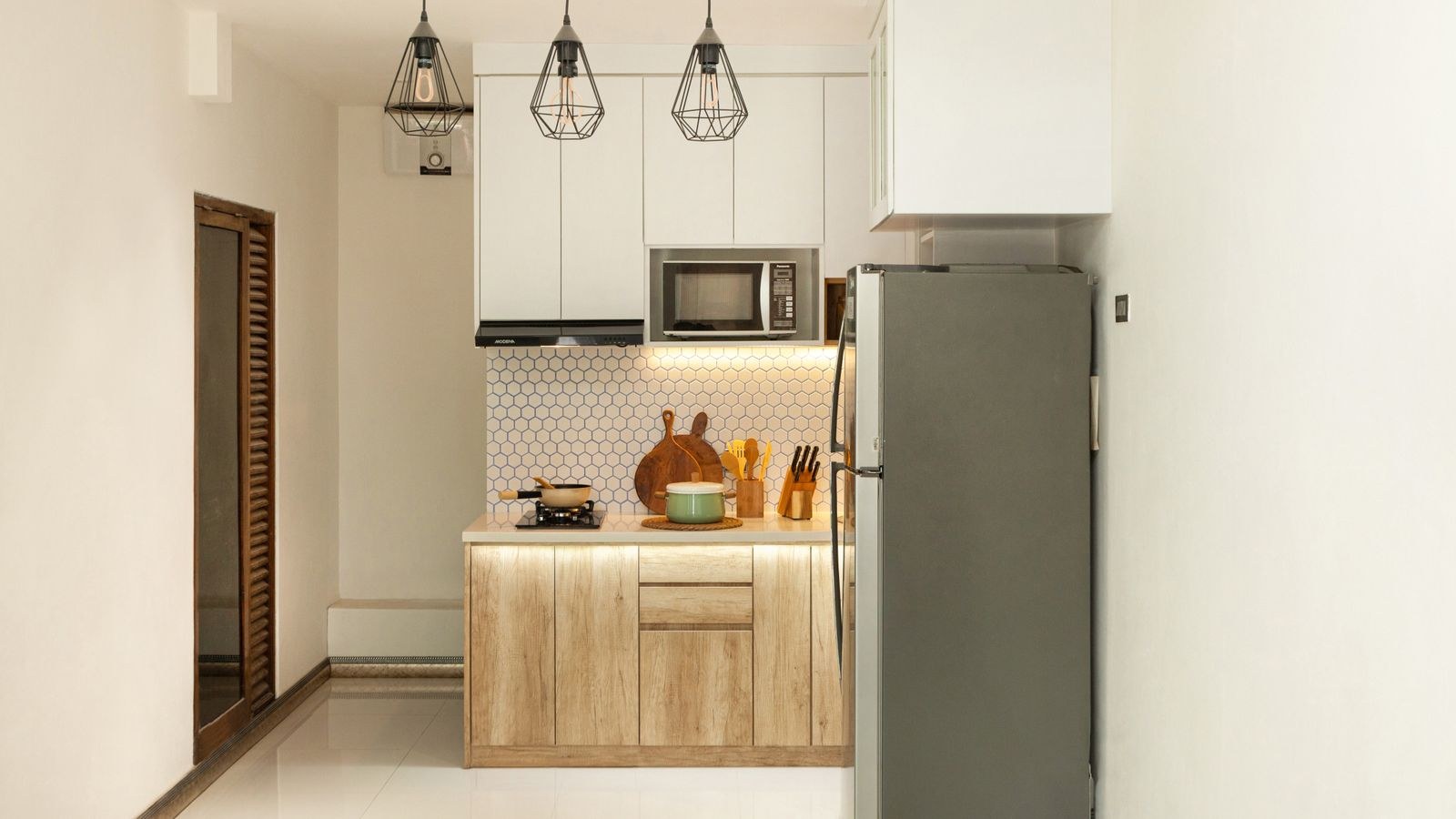 Minimalist gray kitchen with even linear lighting under wooden upper cabinets