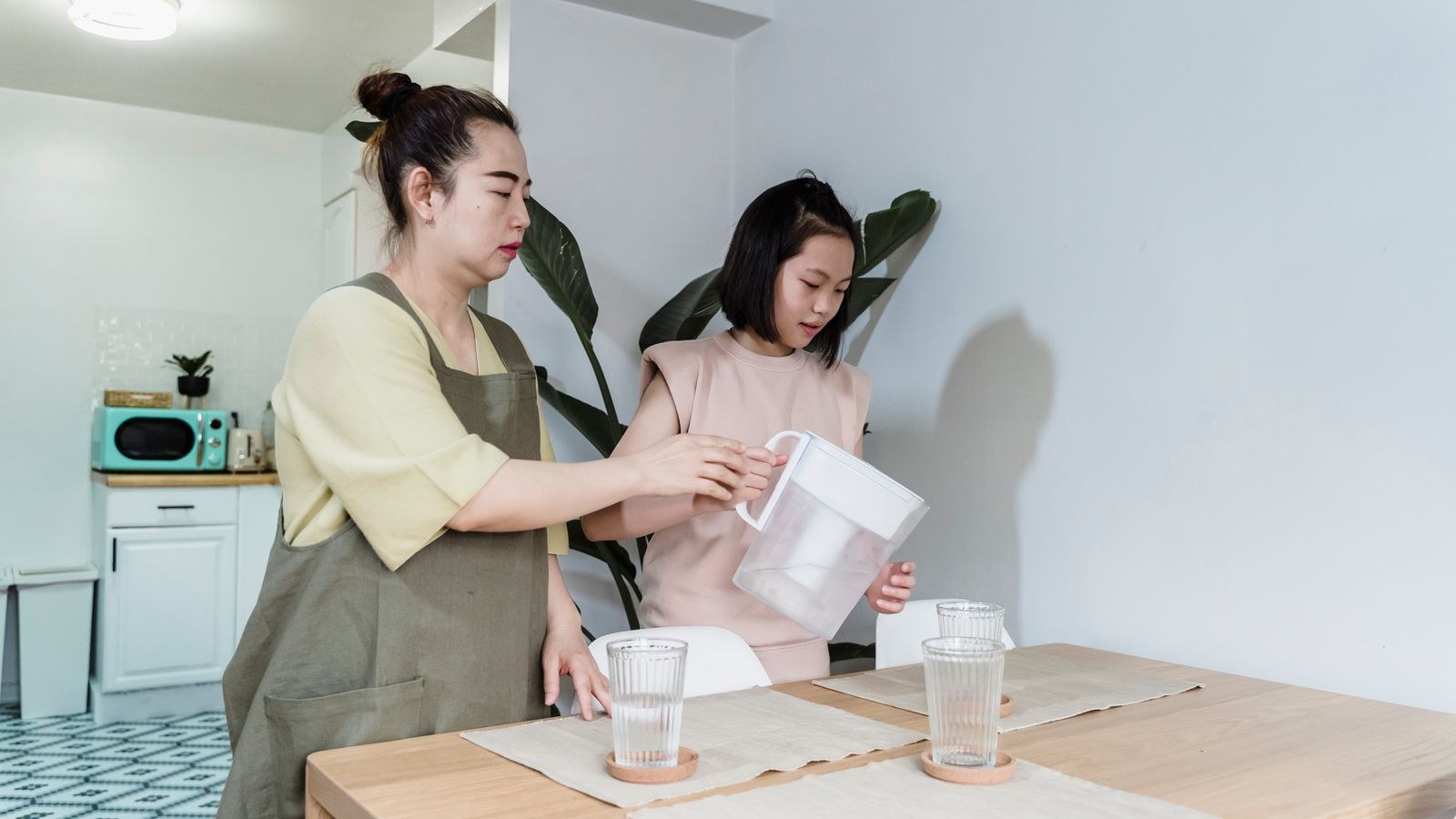 Family filling glasses from a countertop water filter jug in a kitchen