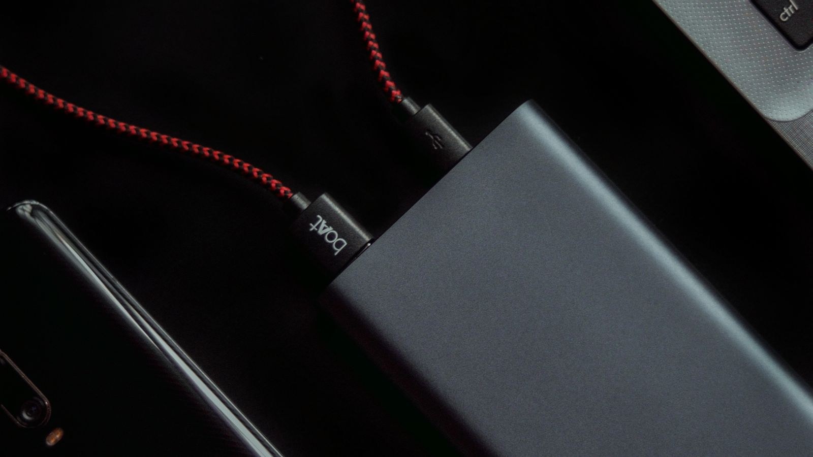 Laptop smartphone and power bank connected by USB-C cables on a desk