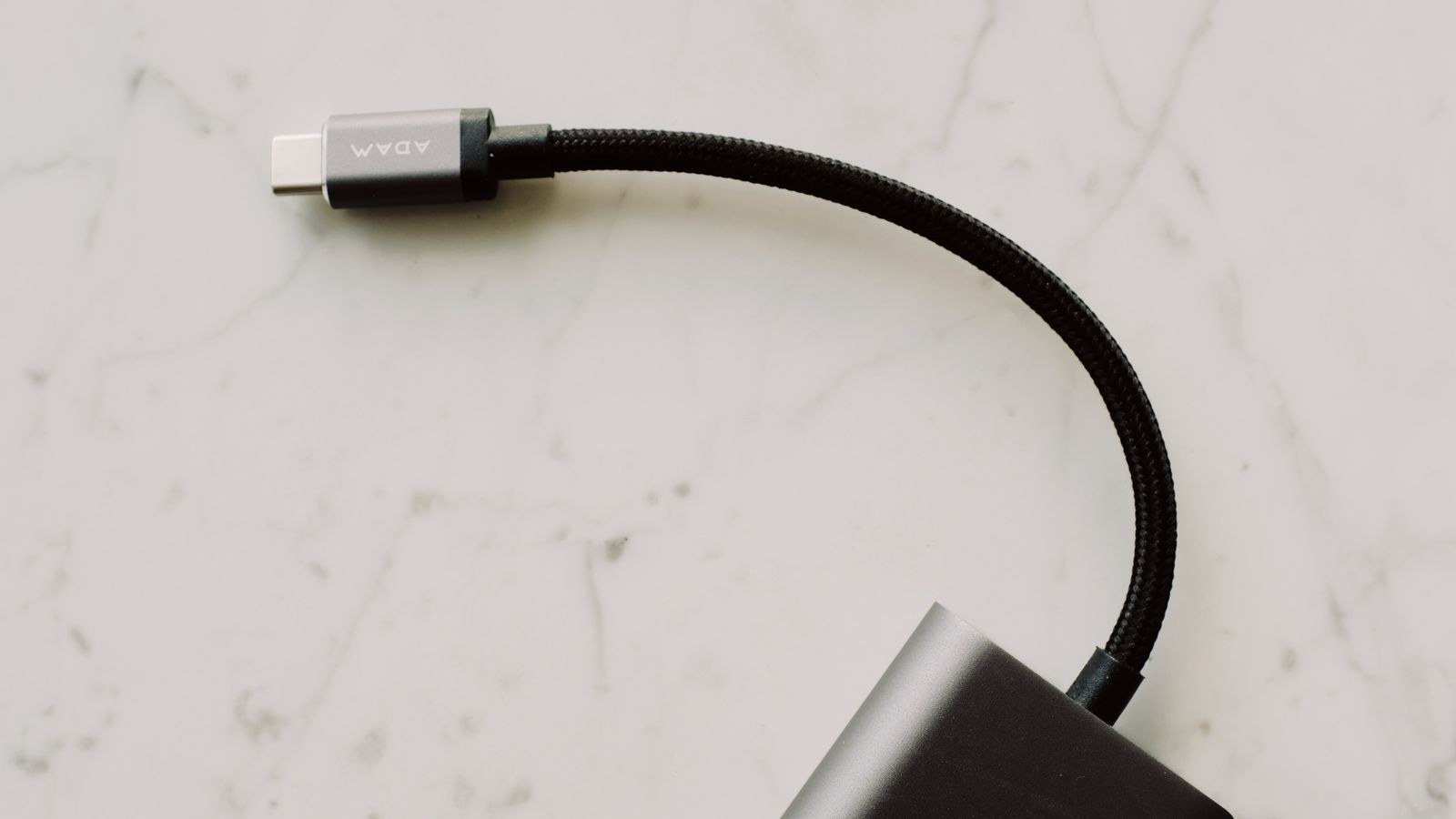 Black braided USB-C cable coiled on a marble surface