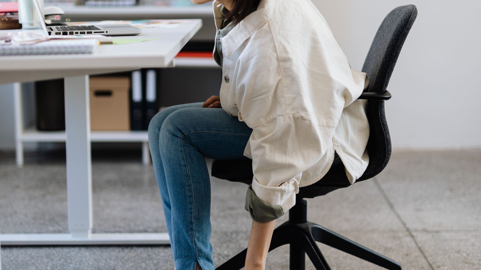 Person seated at a desk with feet supported and knees at a neutral angle