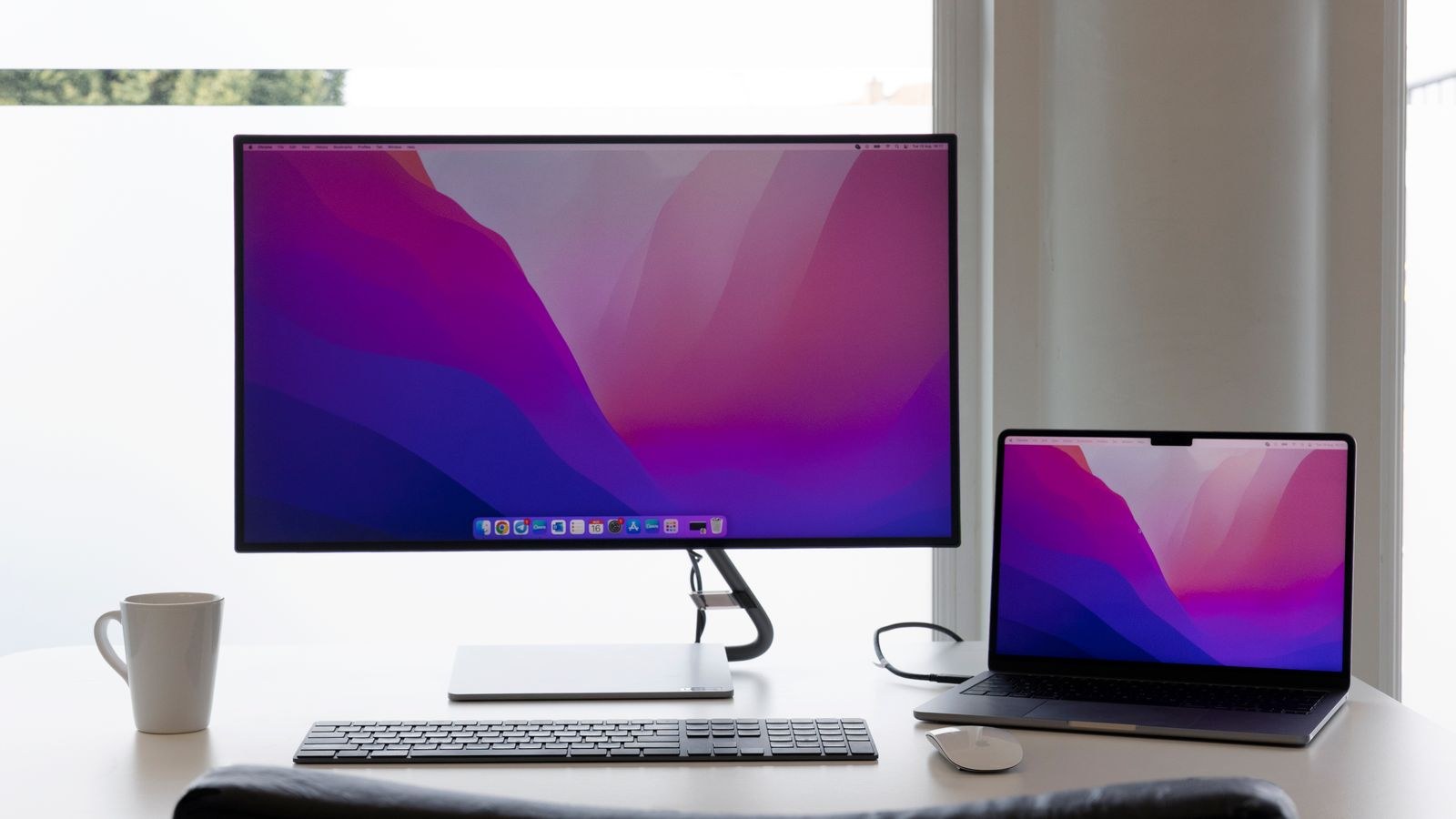 Minimalist workspace with dual monitors, keyboard and a laptop on a clean desk