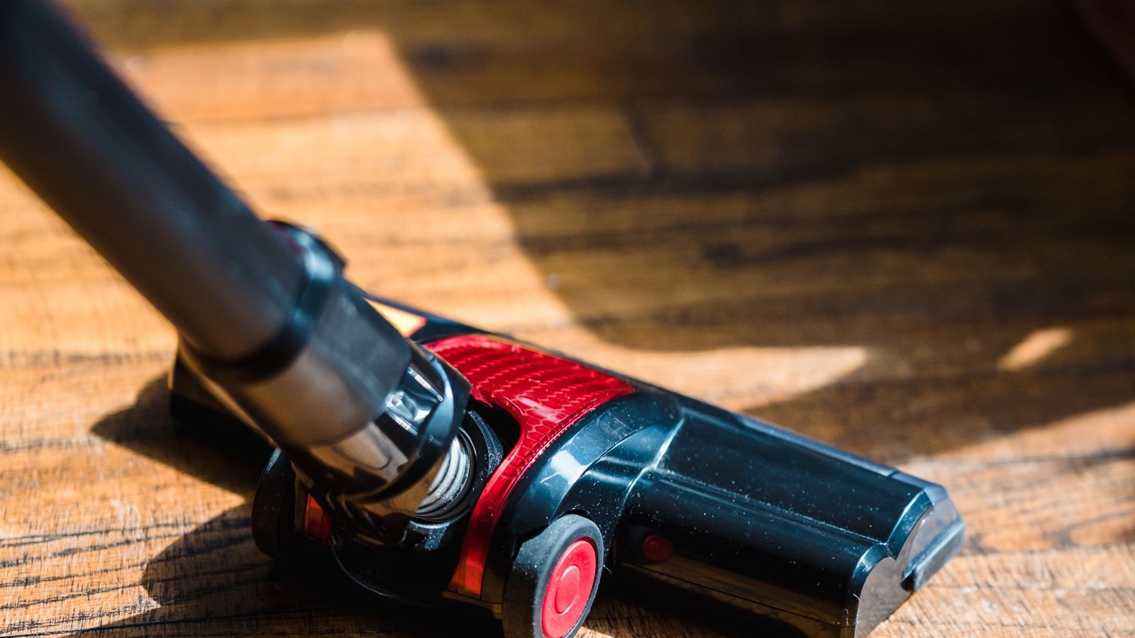 Close up of a vacuum cleaner head cleaning a wooden floor