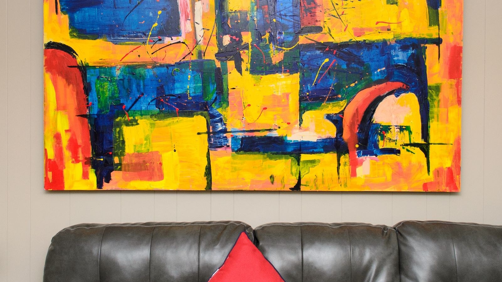 Large abstract painting hung above a leather sofa in a living room