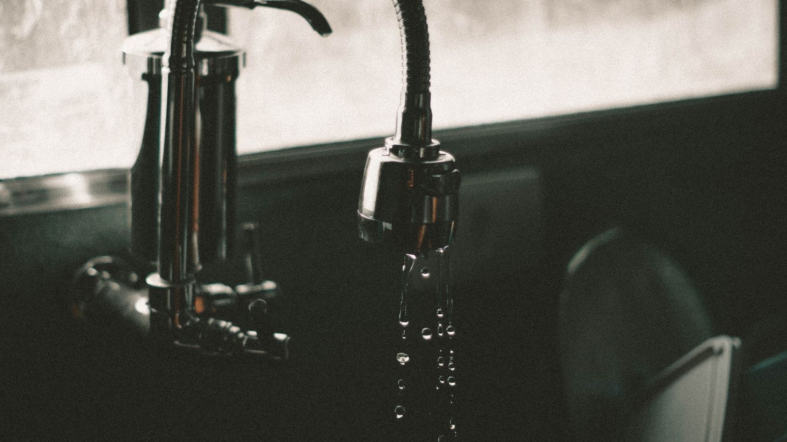 Kitchen faucet with water droplets showing hard water spotting on the sink
