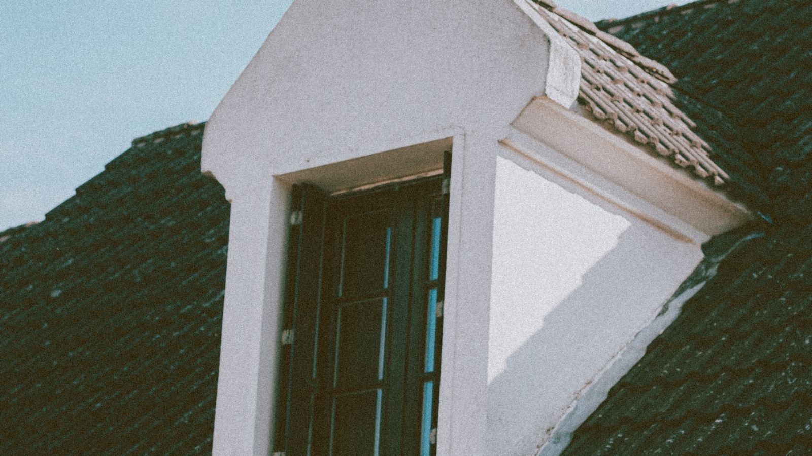 Attic window and roof vent on a residential house roofline