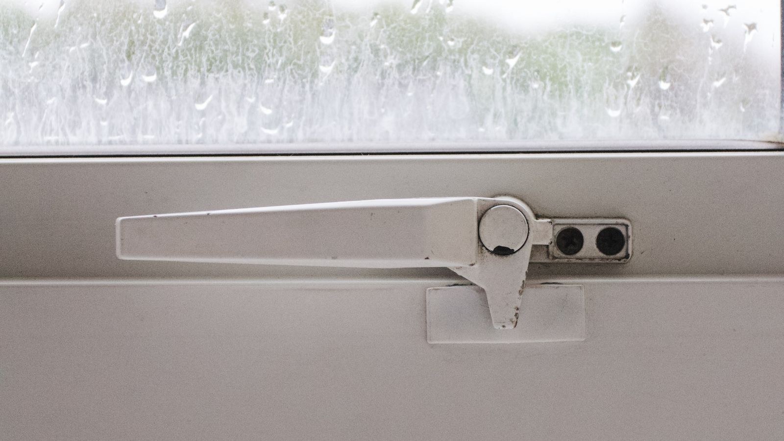 Closed and latched home window viewed from inside on a rainy day