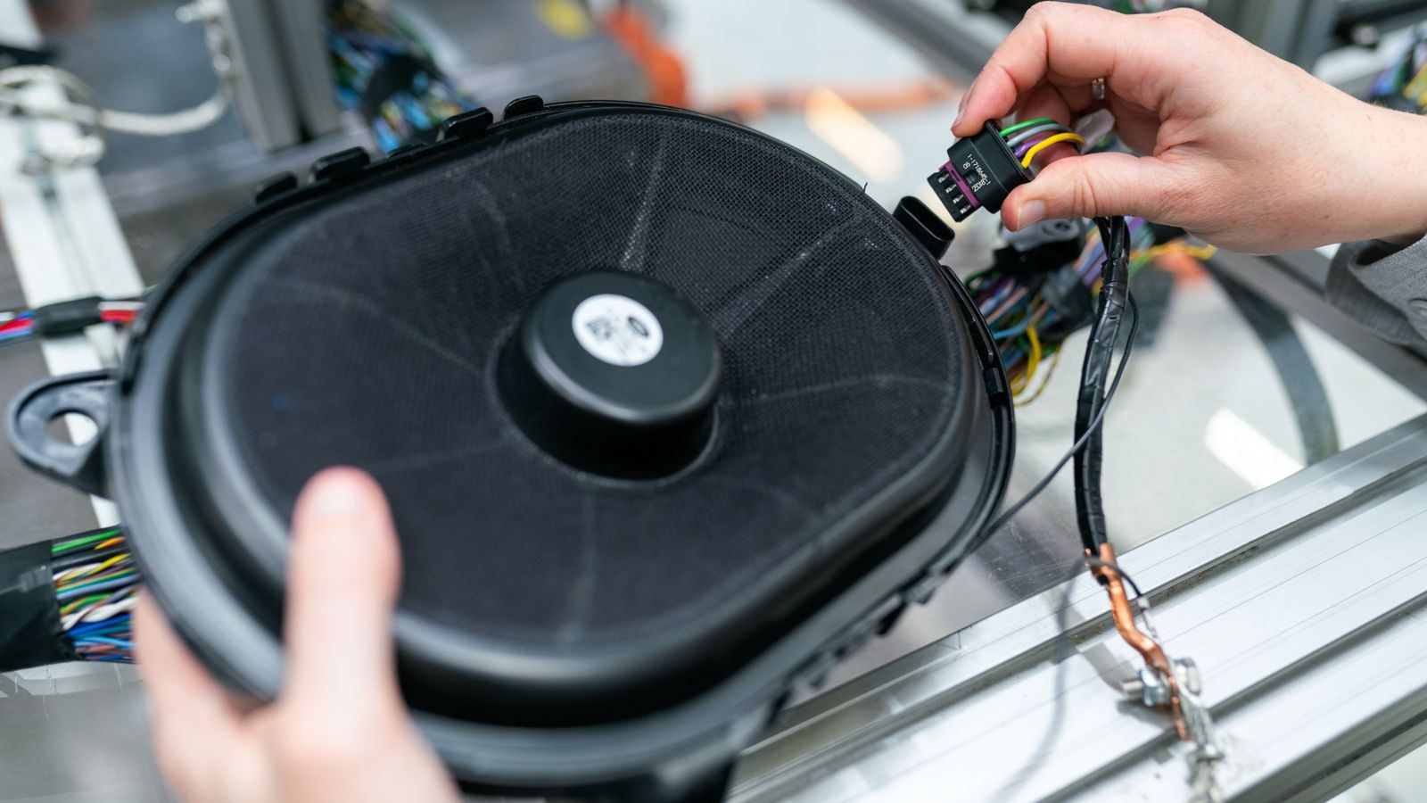 Technician terminating speaker cable on a loudspeaker driver assembly