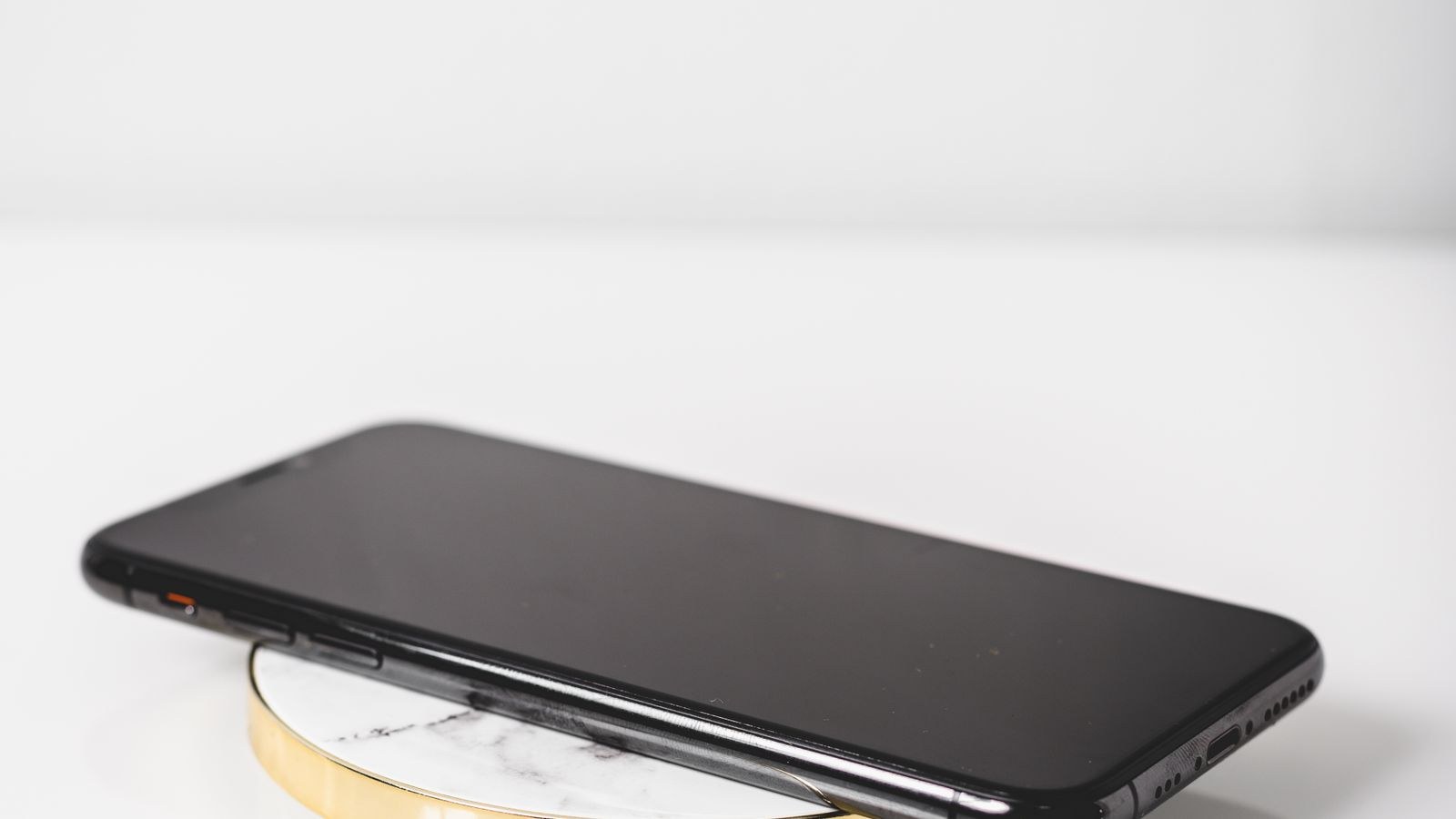 Black smartphone charging on a wireless charging pad against a white background