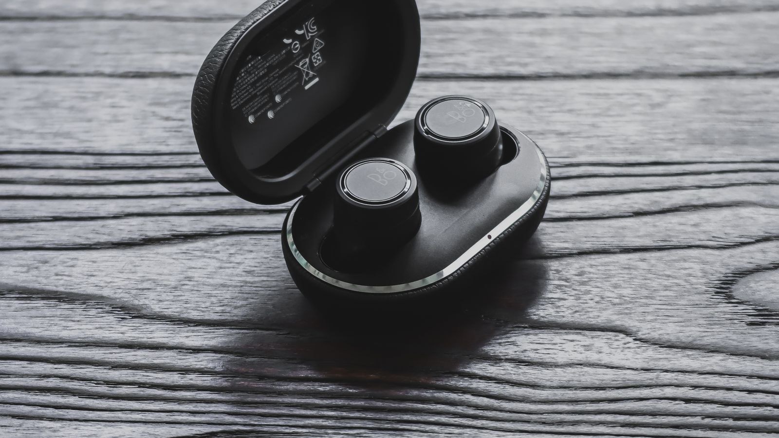 True wireless earbuds in an open charging case on a wooden surface